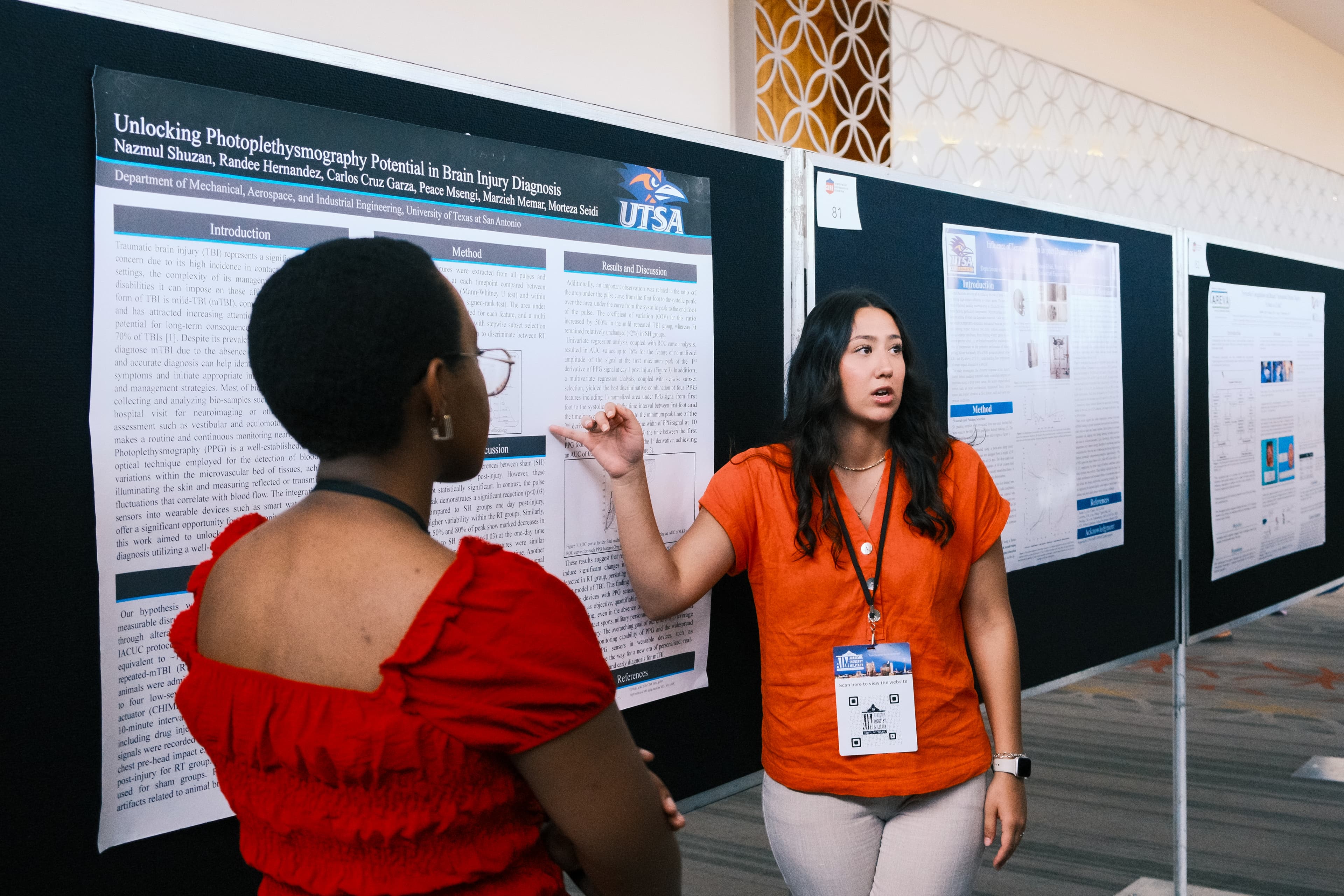 A researcher presents her poster to a conference attendee